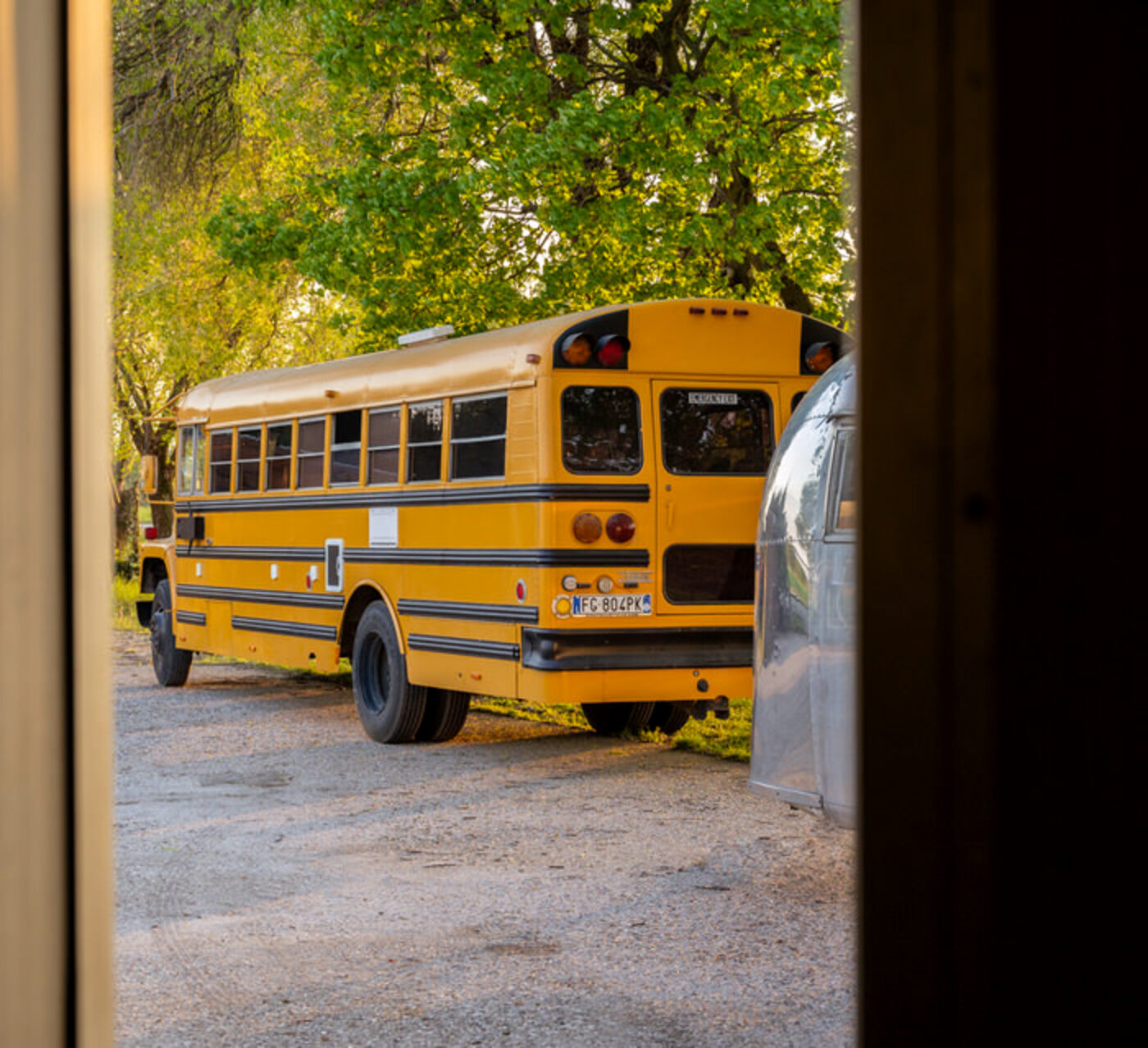 The school bus seen through the opening of a large shed door, framed by the dark edges of the structure.